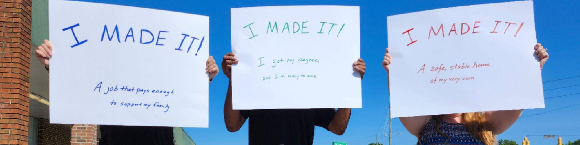 Three persons holding signs that say "I Made It!"